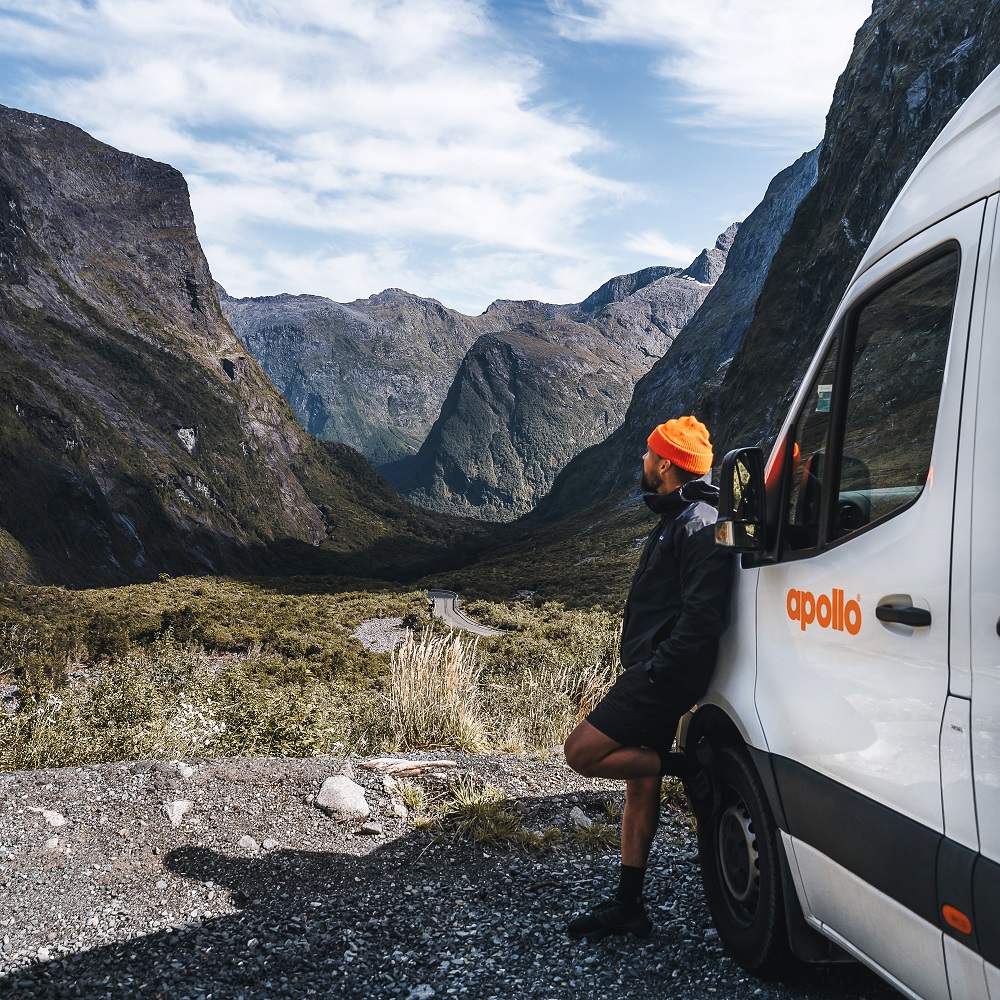 Man leans against Apollo campervan hire admiring the New Zealand mountains